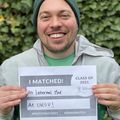Douglas Rice, a caucasian male wearing a beanie hat, smiles while holding a sign that says "I matched!"