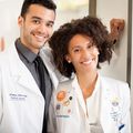 Shane Hervey and Kelley Butler, two Black adults, pose together wearing white doctor coats