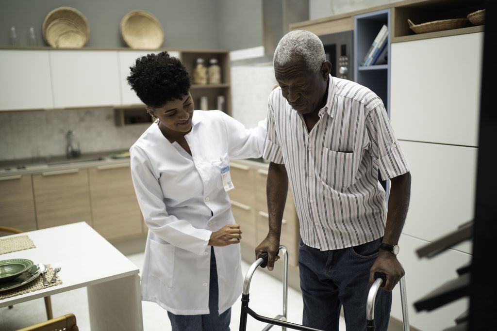 a healthcare worker assists a senior Black man with a walker