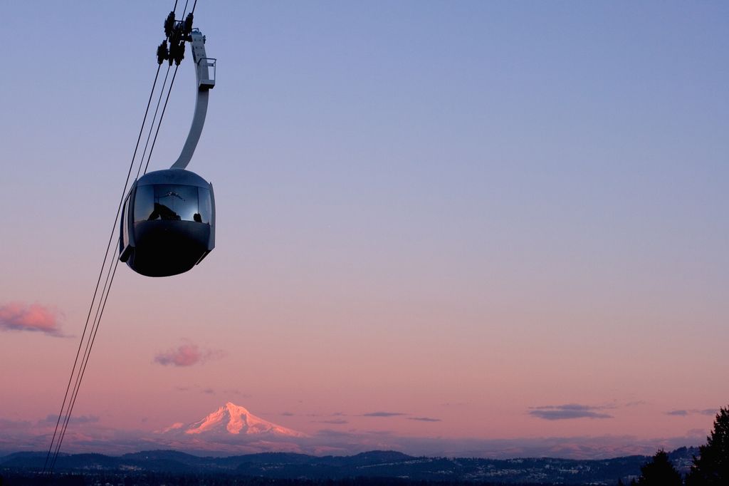 Portland Aerial Tram in silhouette at sunrise, with Mt. Hood visible against the pink and purple sky