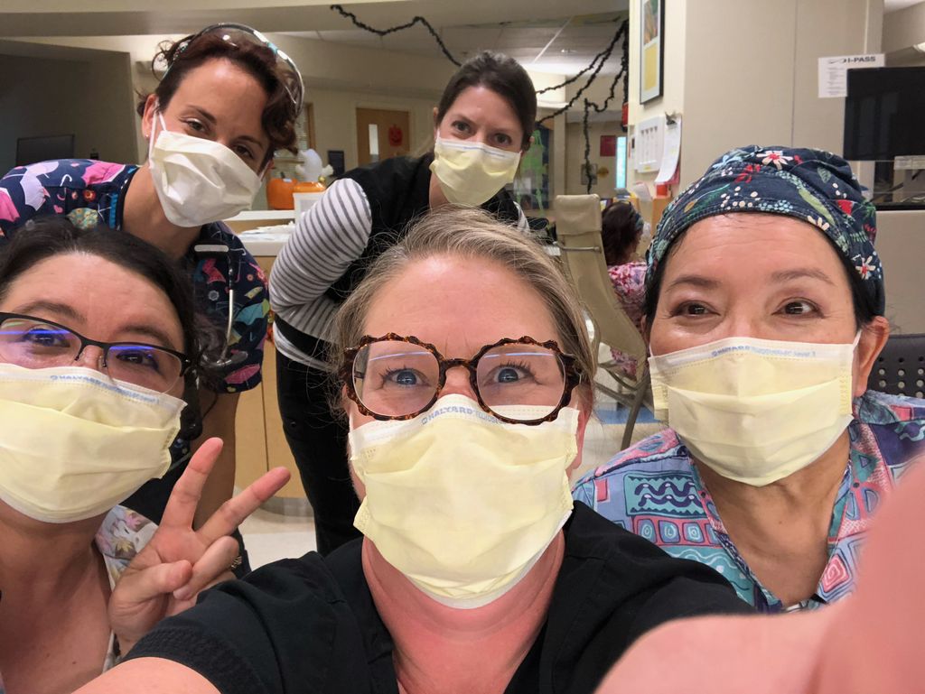 A group of five women wearing face masks smile for a group photo.