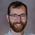 close-in headshot of Daniel Towns D.O., a smiling, bearded ginger man in glasses