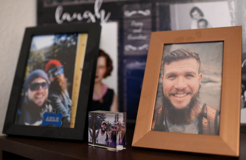 Framed photos of a smiling bearded young man line a countertop.