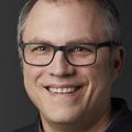 close-in portrait of Erik Amos, a smiling Caucasian male wearing glasses.