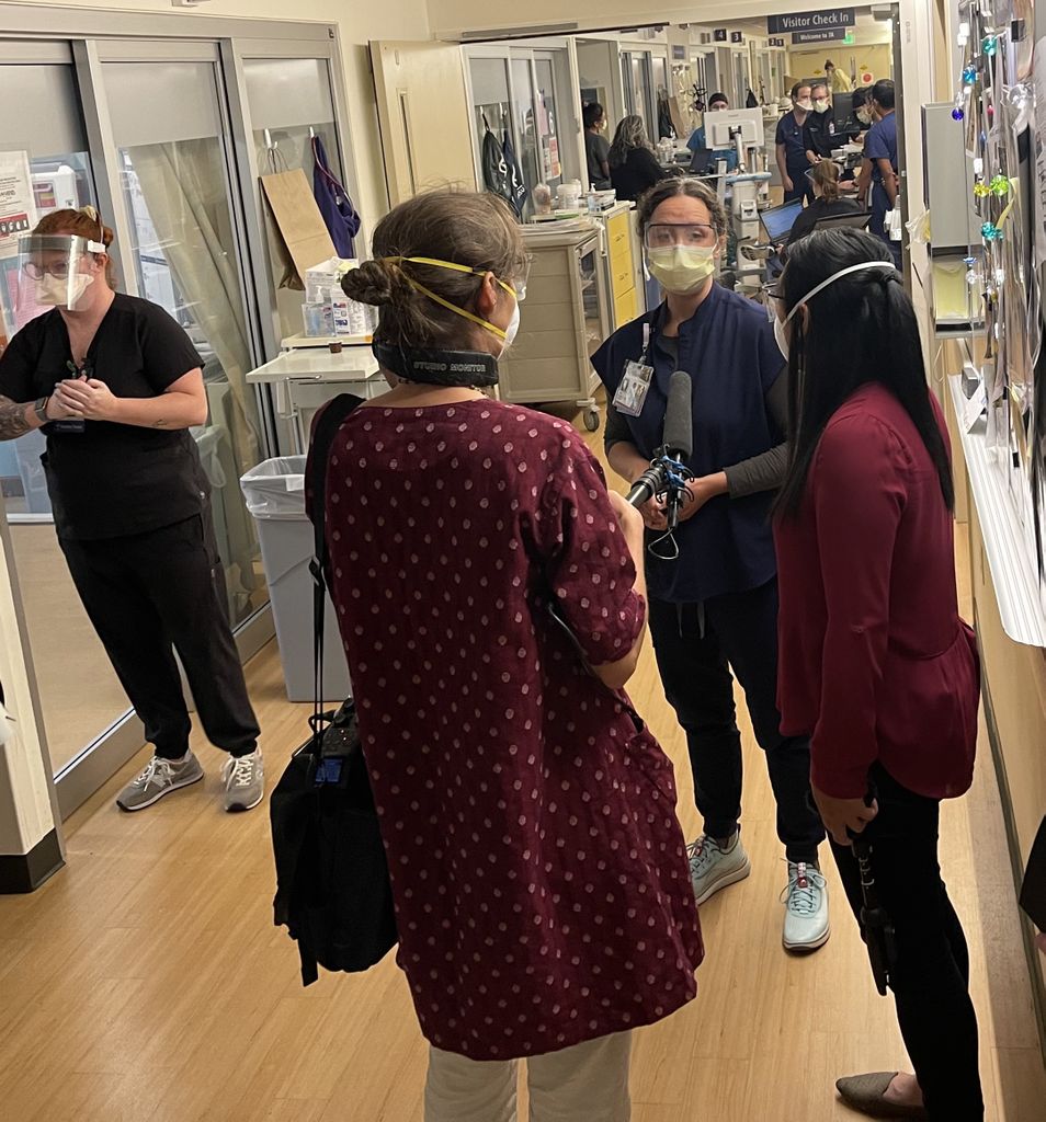 A nurse talks with a cameraman and two reporters in the ICU.
