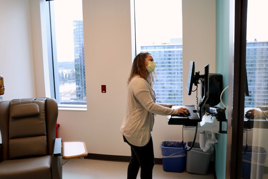 A nurse with long, wavy hair looks at a computer monitor in OHSU's cancer research unit.