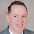 Portrait of Patrick McCormick, M.B.A., a Caucasian man in a grey suit and navy blue tie.