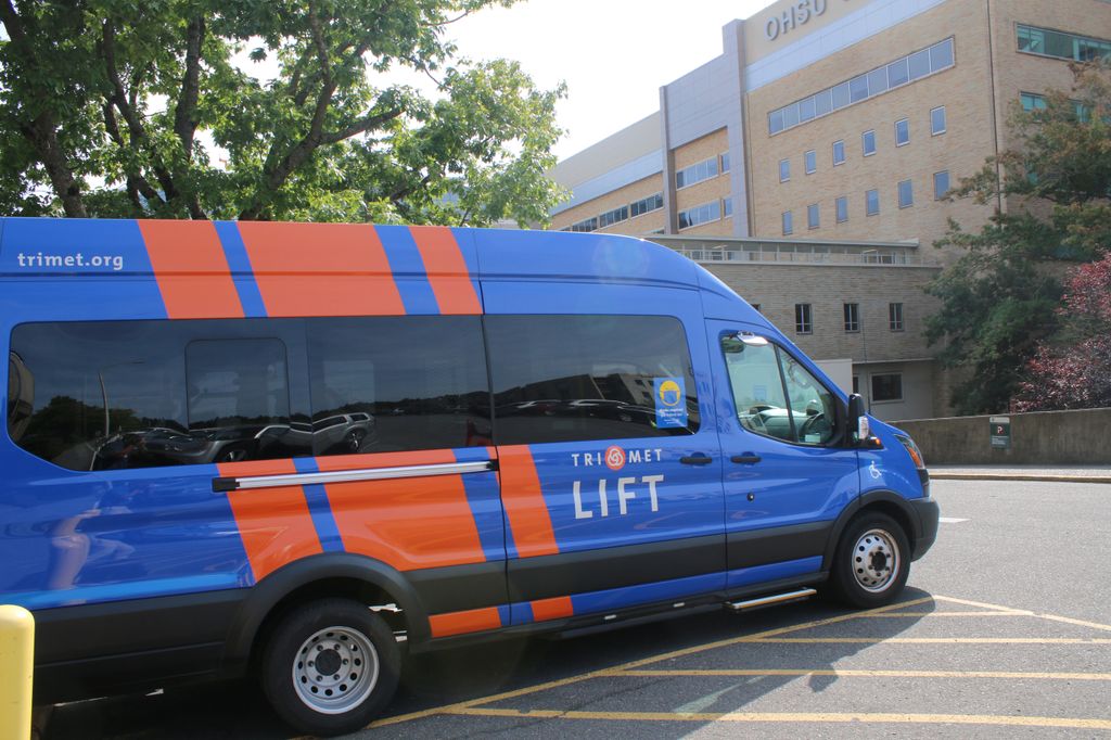 A large blue and orange van labeled 'TriMet Lift' sits parked outside of OHSU hospital.