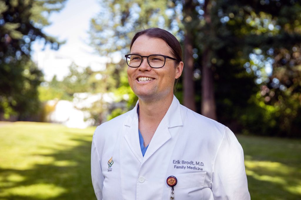 A photo of OHSU's Erik Brodt, M.D., a Native American doctor wearing glasses and a white lab coat. Smiling.