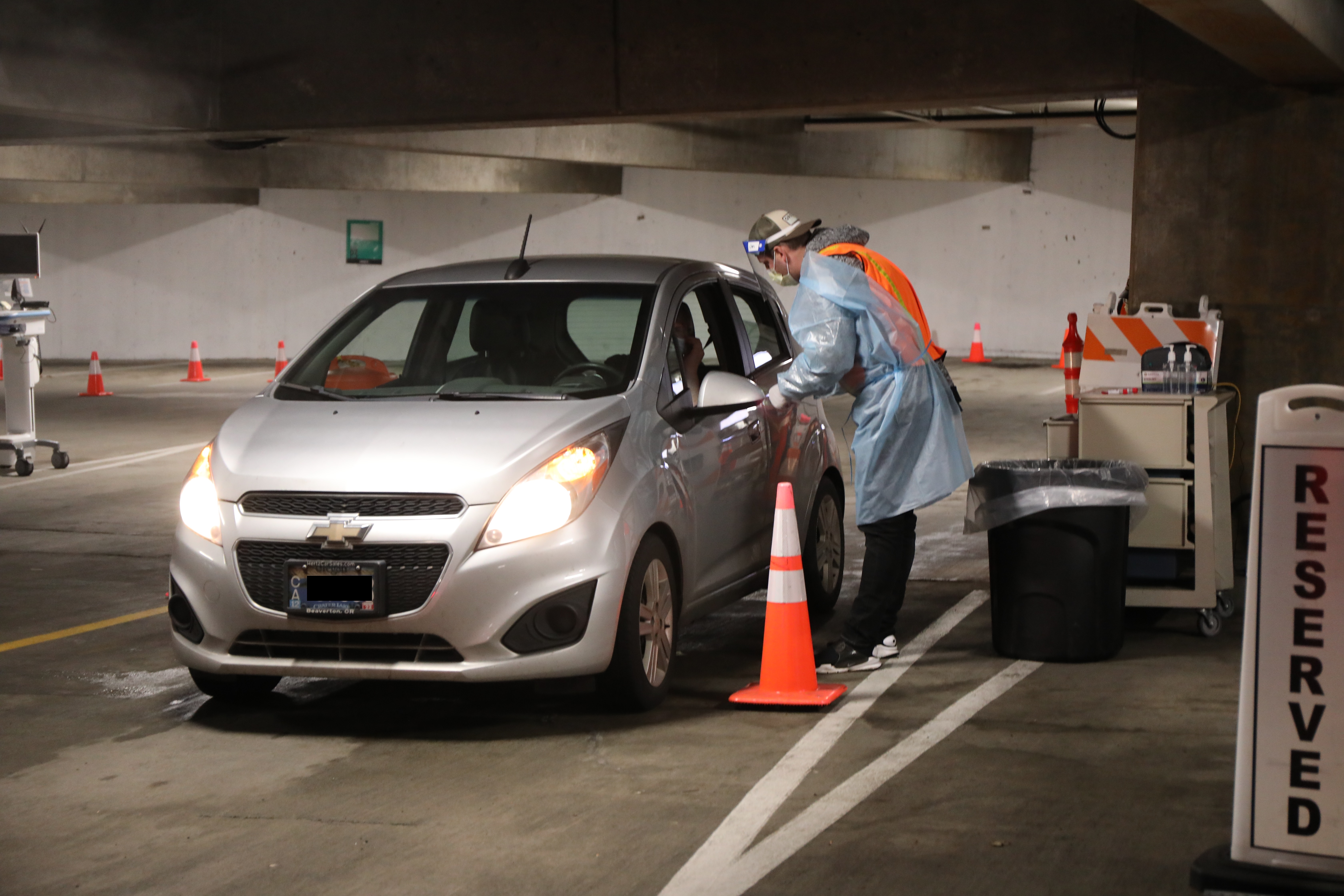 A man waits in his car as an OHSU employee prepares to conduct a COVID-19 test Thursday, Jan. 20, 2022, at OHSU's drive through testing site in Lot D at OHSU on Marquam Hill in Portland. This parking lot is a newly added site for patients to schedule a drive through COVID-19 test. (OHSU/Christine Torres Hicks)