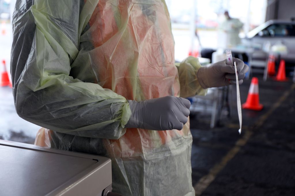 An OHSU employee at the Portland Expo Center holds a COVID-19 test as she waits to test the next vehicle's occupants.