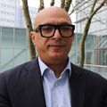 Ahmed Raslan, M.D., a man with no hair smiling, wearing black framed glasses and a suit.
