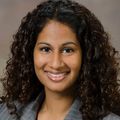 Gina Hawley, Dr.P.H., M.H.A. (OHSU) A person with long brown curly hair, smiling.