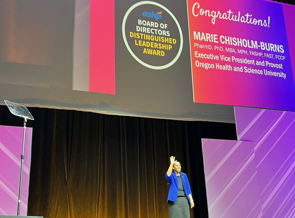 On a stage, OHSU provost Marie Chisholm-Burns has received the ASHP Board of Directors’ Distinguished Leadership Award, which recognizes contributions to excellence in pharmacy practice leadership in acute and ambulatory care settings. (Courtesy)