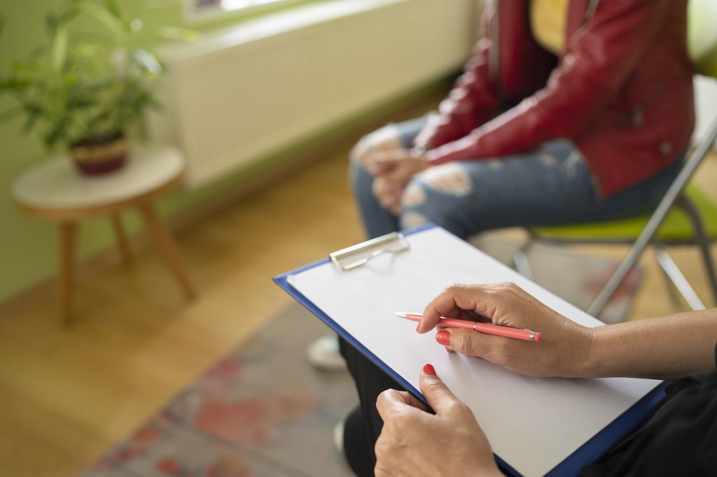 A psychologist takes notes as a teen speaks&nbsp;during a mental health meeting. 