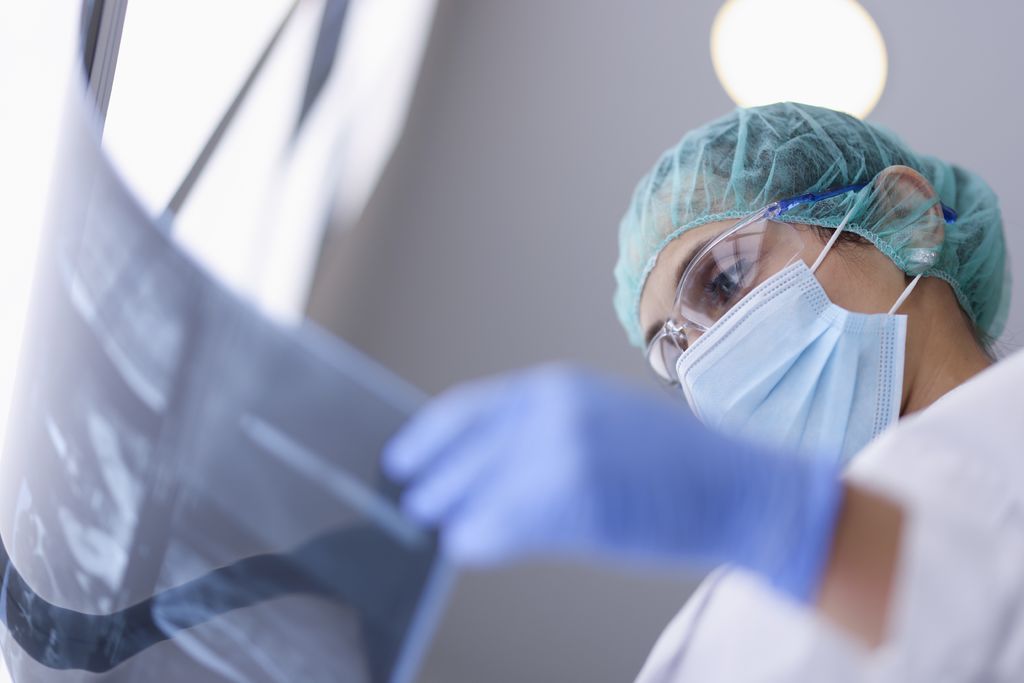A cancer doctor in protective medical mask looks at an X-ray. 