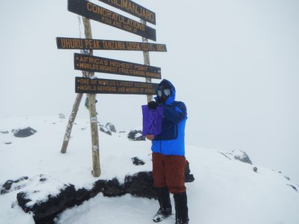 A person atop Mt. Kilimanjaro in a fullbody blue snow suit.