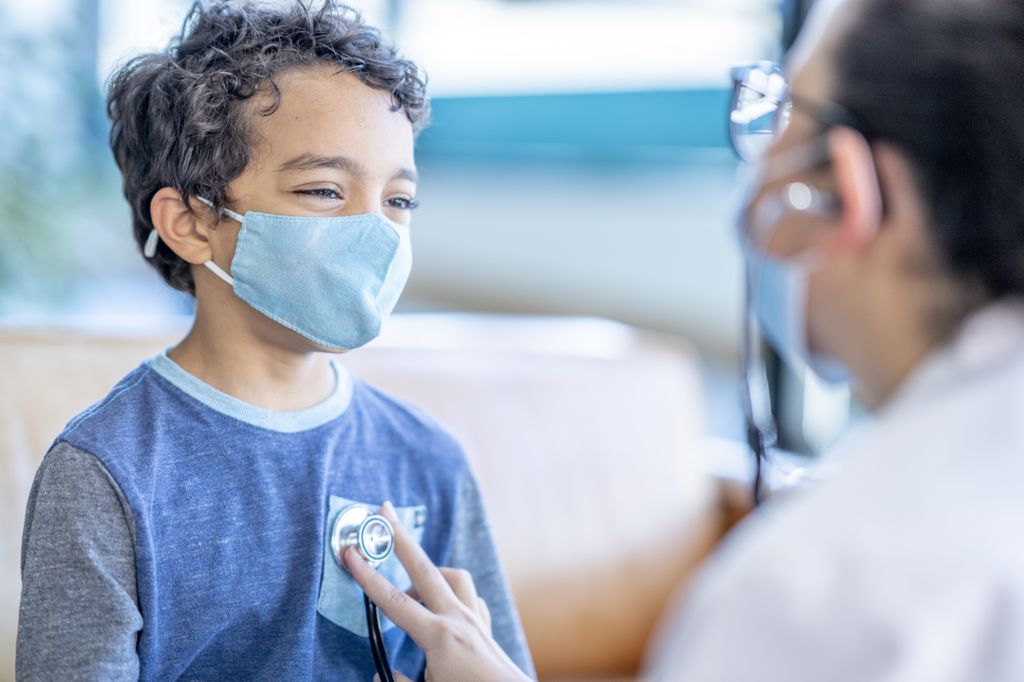 A child in a doctor office as doctor examines and listens to kids' heart.