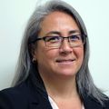 Heather Wong is a person with shoulder-length gray and black hair, wearing glasses, and a suit, smiling.