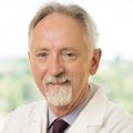 Kim Burchiel, M.D., stands near a window at OHSU in his white coat.