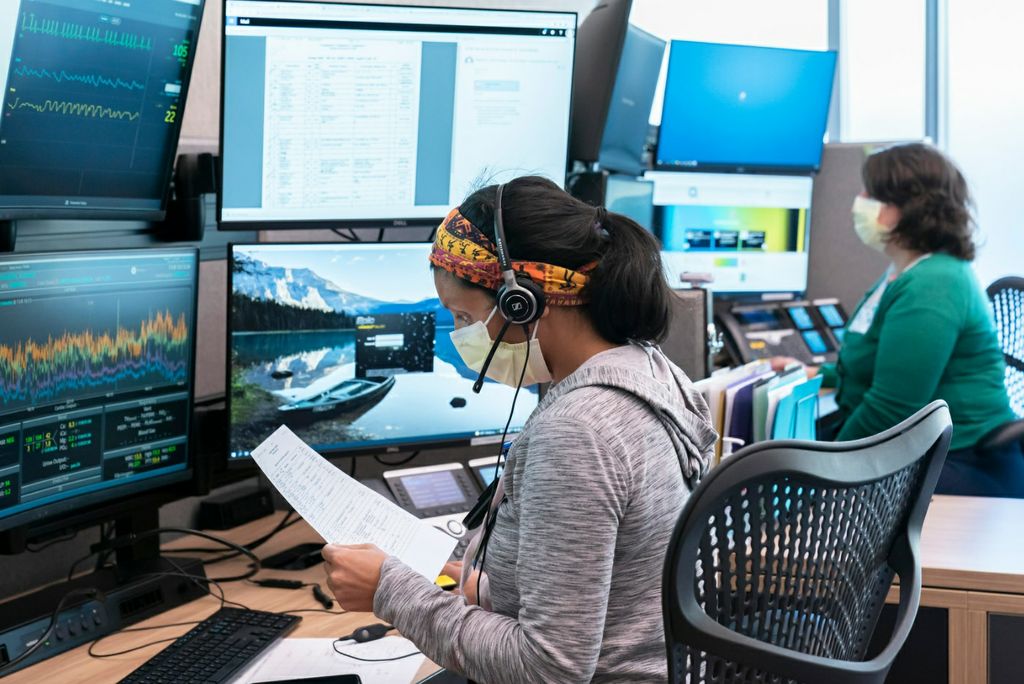 A virtual health program facilitator looks at documents and screens to analyze a patient's information over the computer.