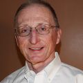 Rick Johnson, Ph.D. (Courtesy) A man with glasses, short gray hair in a white shirt, smiling against a brown background.