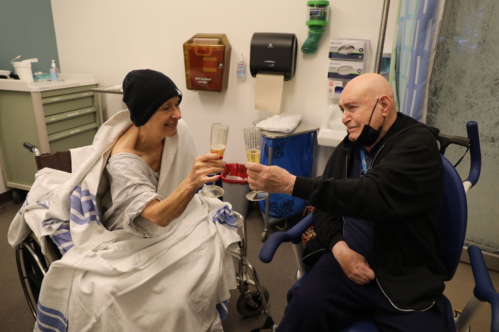 Patient Jean Henderson and her husband Larry celebrate after Jean's high-frequency ultrasound brain surgery led by OHSU neurosurgeon Ahmed Raslan and his team on Wednesday, March 30, 2022. Jean Henderson, holding her glass of sparkling cider very steadily for the first time in years. She&nbsp;is the first patient to undergo this treatment in Oregon. She has had a tremor for four years, which limited her abilities to care for herself, and this surgery corrected that tremor in her right hand/arm in just a few hours with no incision. (OHSU/Christine Torres Hicks)