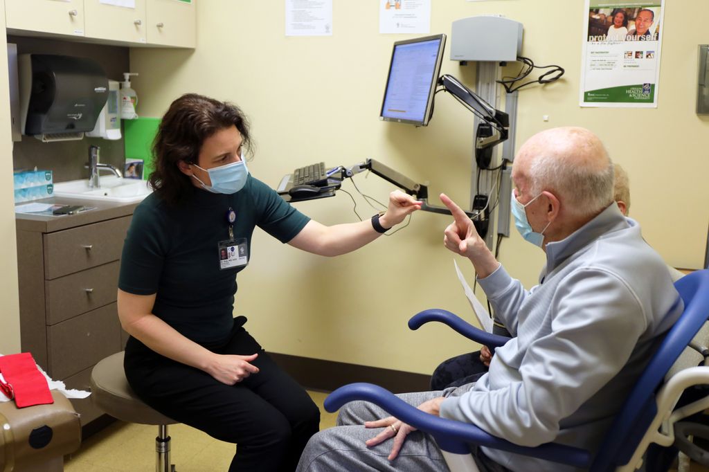 Marian Dale, M.D. checking out patient Bernie Pitz in a doctor office. 