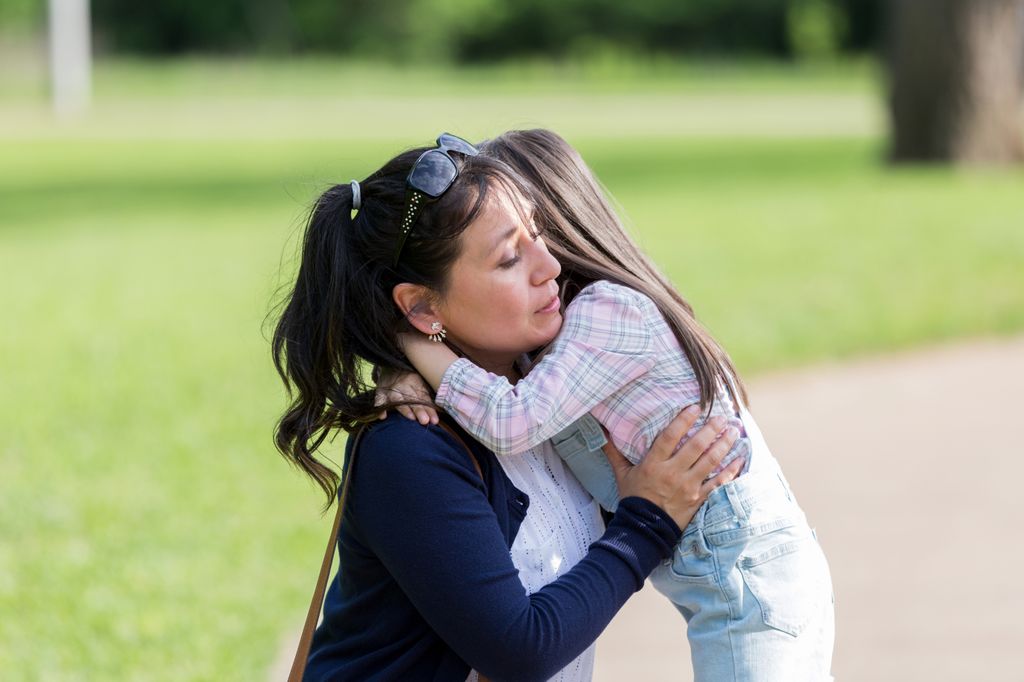 A person embraces a child on grass.After another mass shooting in the United States, OHSU implores all those with the ability to take action by coming together and implementing steps to stop the violence. (Getty Images)