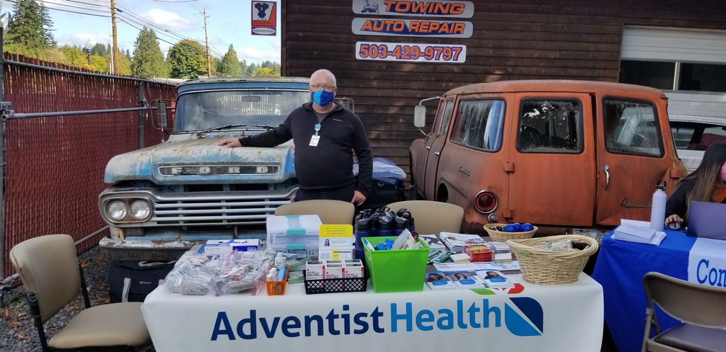A man attends the Adventist Health info booth in a car yard. 