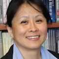 Seiko Izumi Ph.D. R.N. (OHSU) stands near a bookshelf full of books.