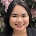 Maria Theresa Dizon (Courtesy of Maria Dizon) smiles in front of a flowered bush.