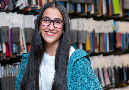 Riddhi Mahajan stands near fabric swatches.