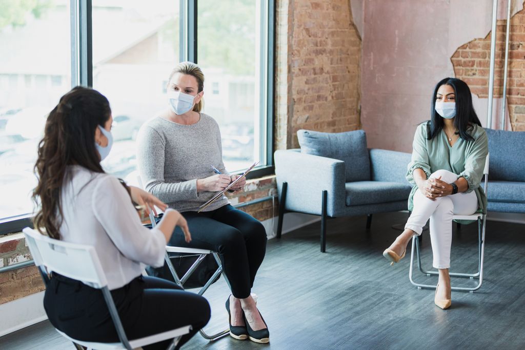 Group of three women talking with masks on.