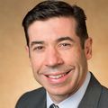 Antonio Frias, M.D., stands against a yellow-orange background.