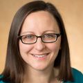 Victoria Roberts, Ph.D., stands against a yellow-orange background.