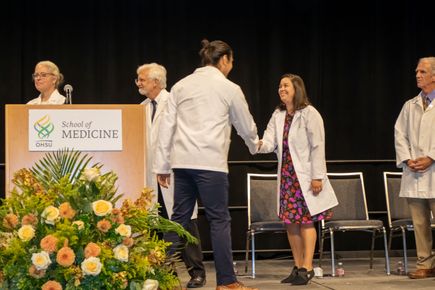 Allison Empey, M.D., assistant professor of pediatrics, congratulates Jaime Contreras, a member of the entering M.D./Ph.D. class, upon receiving his white coat. (OHSU/Christine Torres Hicks)