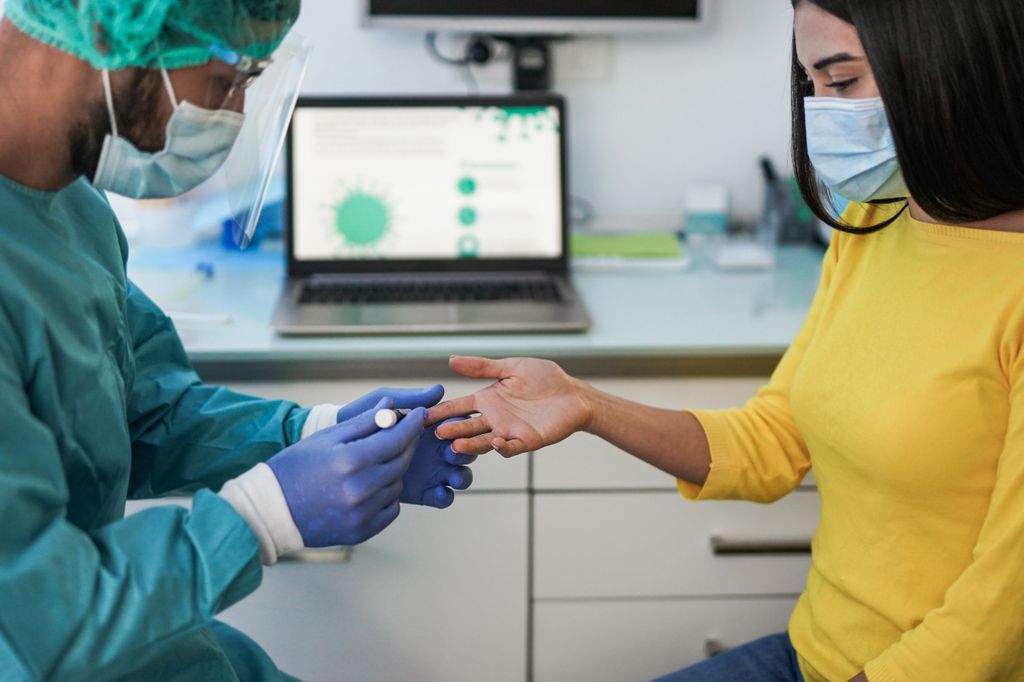 A health care worker tests the blood-sugar level of a patient.