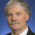 Charles T. Roberts, Ph.D., is next to a blue background.