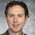 Benjamin Morasco, Ph.D., near a gray background.
