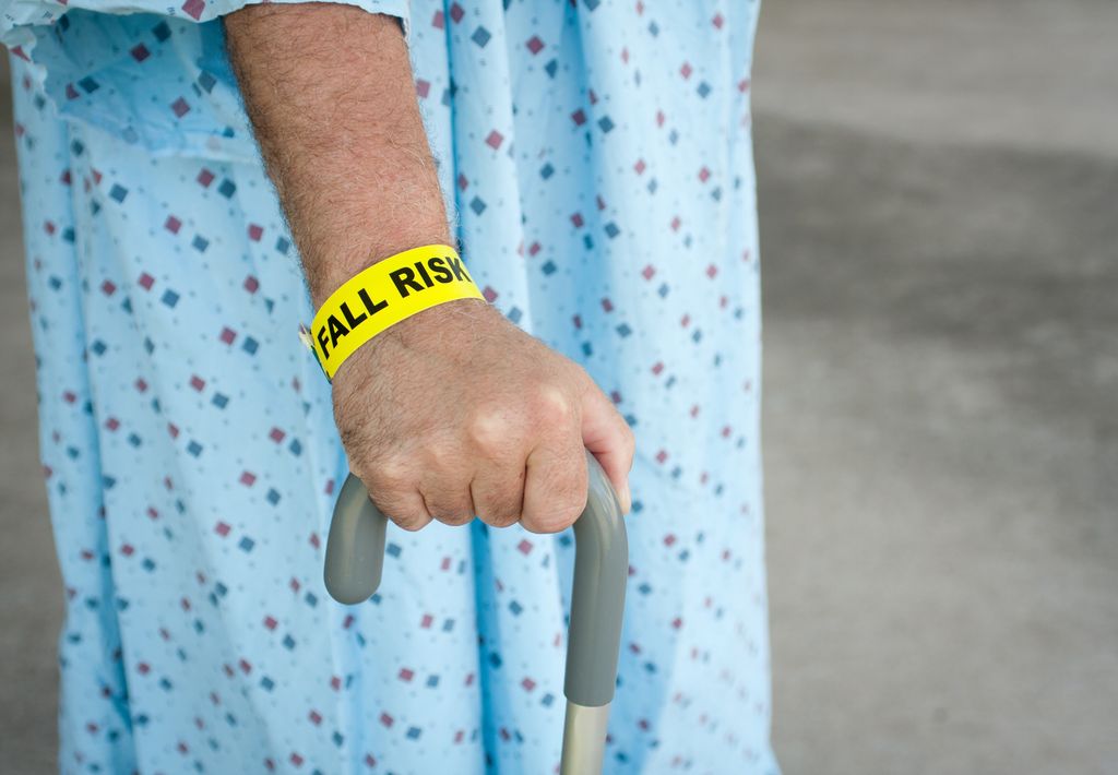 An elderly man wears a fall risk bracelet while at a hospital.