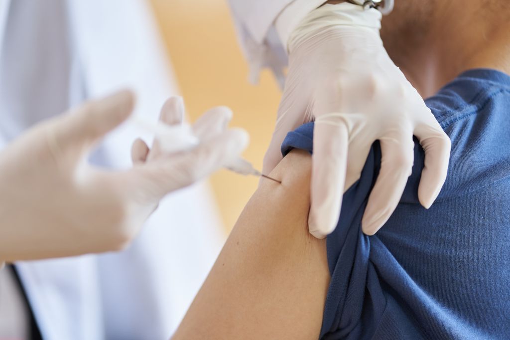 Person injection another person in the left arm with a vaccination.