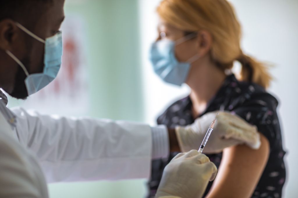 A woman gets injected with the COVID-19 vaccine by a doctor.