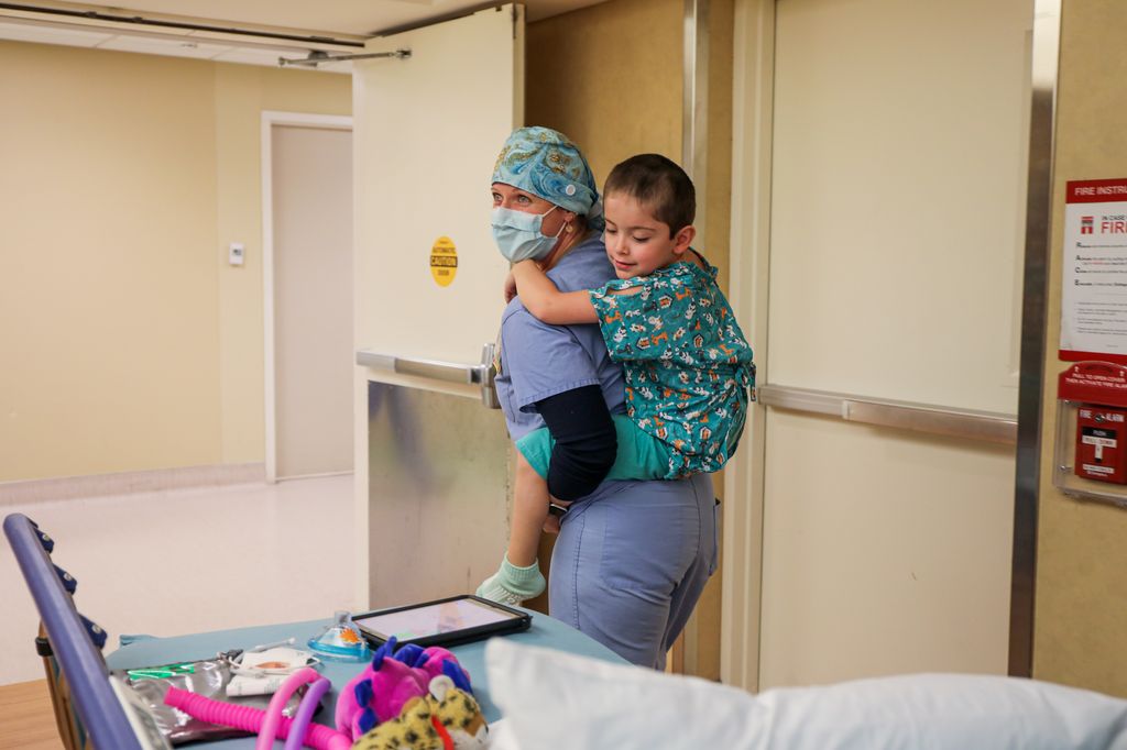 Jess Calvert, especialista en Vida Infantil de Doernbecher Children’s Hospital, lleva a un pequeño paciente al quirófano para una cirugía espinal. (OHSU/Christine Torres Hicks)