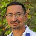 Ashok Muralidaran, M.D., tiene cabello negro corto, anteojos y usa una bata blanca en el jardín del Hospital Infantil Doernbecher.