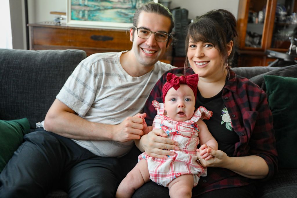 Chase y Gabrielle Zielinski se sientan en casa el martes con su hija, Sophie. El 30 de julio, Gabrielle fue rápidamente llevada a OHSU para una cirugía de emergencia de la columna vertebral que revirtió la parálisis que ocurrió por un simple estiramiento. (OHSU/Christine Torres Hicks)