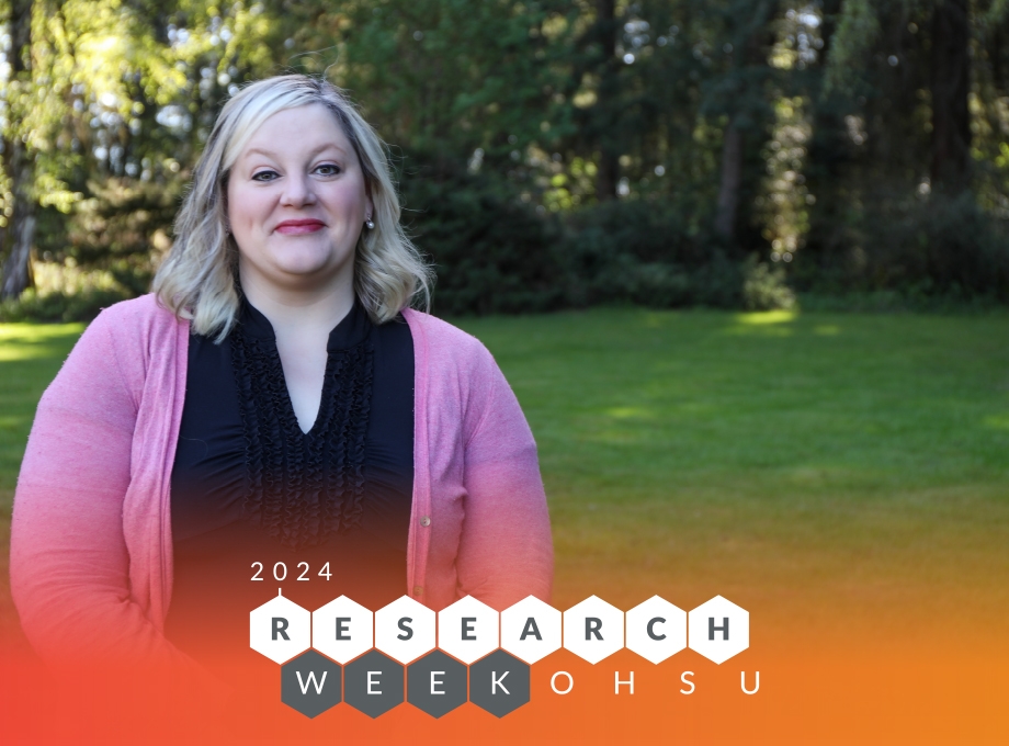 Bethany Samuelson Bannow - Semana de investigación 2024 - tiene el pelo rubio corto, lleva una blusa negra y un suéter rosa y está parada en el césped de OHSU en una mañana de primavera.