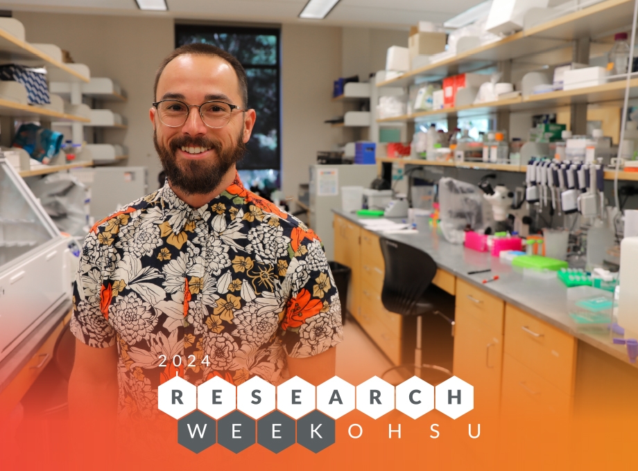 Brandon Wilder - Semana de investigación 2024. Brandon Wilder tiene el pelo corto y castaño, gafas y una camisa con botones florales. Él está sonriendo mientras está de pie en su laboratorio.