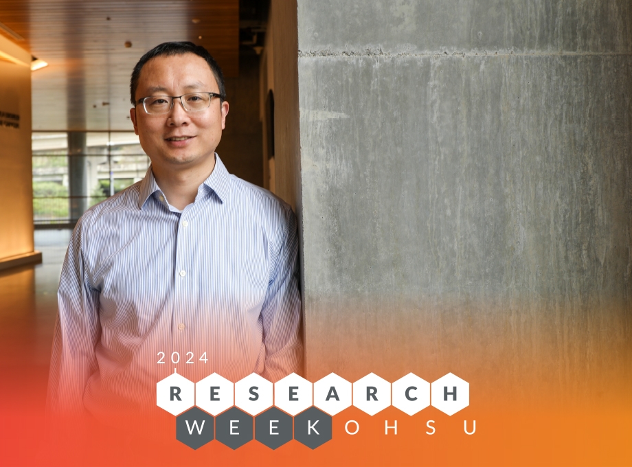 Zheng Xia - Research Week 2024 - has short dark hair, glasses, and a light blue and white pinstriped button-up shirt. Xia is standing in the halls of the Knight Cancer Institute.