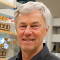Klaus Früh (Frueh), Ph.D., tiene cabello corto plateado, una chaqueta de OHSU y sonríe en el laboratorio.
